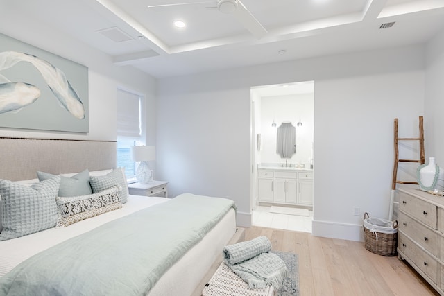 bedroom featuring light wood-type flooring, ceiling fan, and connected bathroom