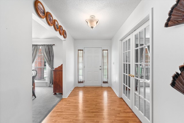 entryway with light hardwood / wood-style floors and a textured ceiling