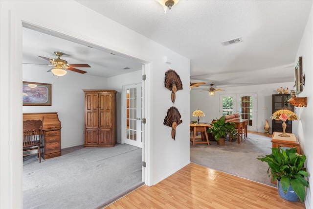 foyer featuring ceiling fan, french doors, light hardwood / wood-style floors, and a textured ceiling