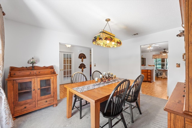 dining space featuring a textured ceiling, light wood-type flooring, and ceiling fan