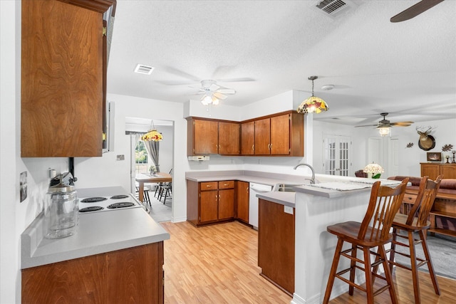 kitchen featuring light hardwood / wood-style floors, pendant lighting, white appliances, kitchen peninsula, and a textured ceiling