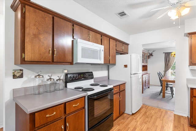 kitchen featuring ceiling fan, a textured ceiling, light hardwood / wood-style flooring, and white appliances