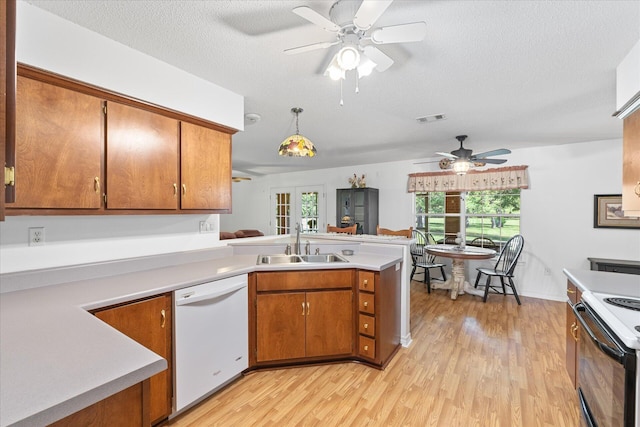 kitchen with white appliances, hanging light fixtures, sink, and light wood-type flooring