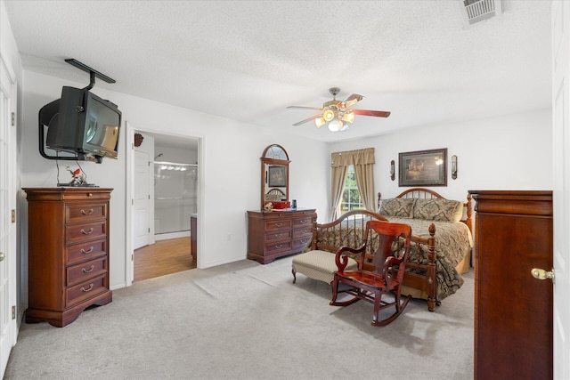 bedroom with light carpet, ceiling fan, connected bathroom, and a textured ceiling