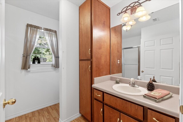 bathroom with hardwood / wood-style floors, a shower with shower door, vanity, and a textured ceiling