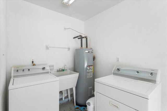 laundry room featuring separate washer and dryer, water heater, sink, and a textured ceiling