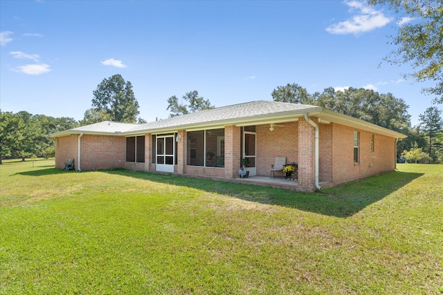 rear view of house with a yard, a sunroom, and a patio area