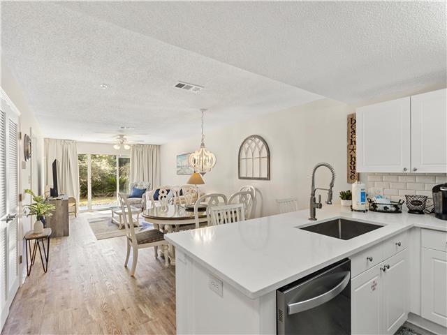 2076 Scenic Gulf Dr Unit 1013, Miramar Beach, FL 32550 - kitchen featuring a textured ceiling, stainless steel dishwasher, a sink, a peninsula, and open floor plan