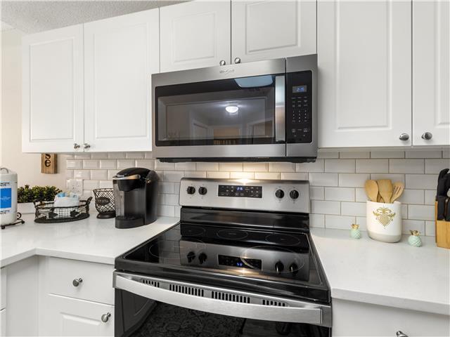 2076 Scenic Gulf Dr Unit 1013, Miramar Beach, FL 32550 - kitchen with light countertops, decorative backsplash, white cabinets, and stainless steel appliances