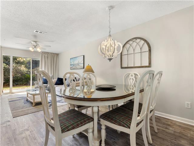 2076 Scenic Gulf Dr Unit 1013, Miramar Beach, FL 32550 - dining space featuring visible vents, wood finished floors, baseboards, a textured ceiling, and ceiling fan with notable chandelier