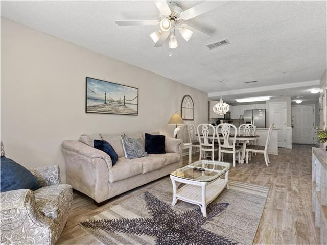 2076 Scenic Gulf Dr Unit 1013, Miramar Beach, FL 32550 - living area with visible vents, a textured ceiling, light wood-style flooring, and ceiling fan with notable chandelier
