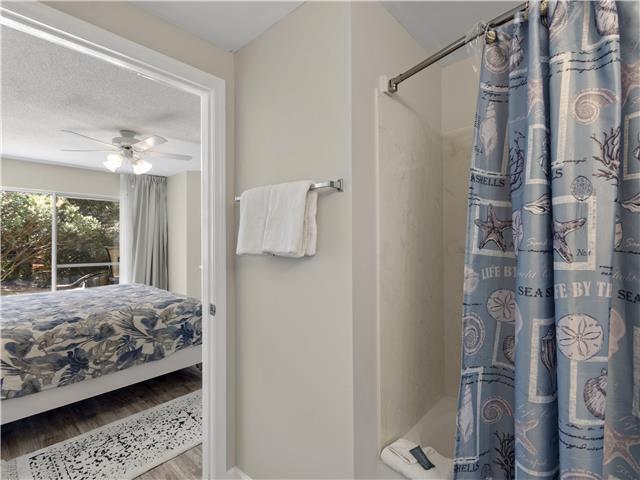 2076 Scenic Gulf Dr Unit 1013, Miramar Beach, FL 32550 - bathroom with a shower with shower curtain, ceiling fan, and wood finished floors