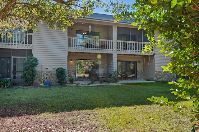 rear view of property featuring a patio, a balcony, and a lawn