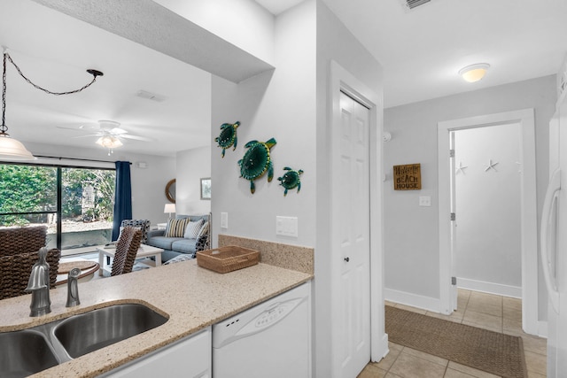 kitchen featuring light tile patterned flooring, ceiling fan, sink, light stone counters, and white dishwasher