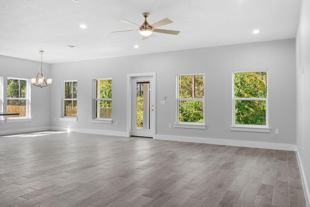 spare room featuring ceiling fan with notable chandelier and light hardwood / wood-style floors