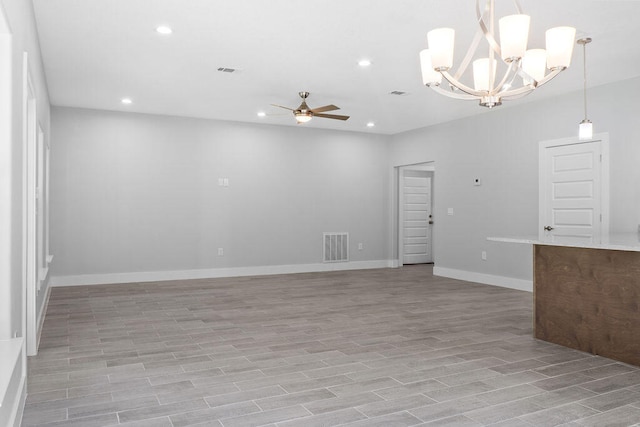 empty room featuring ceiling fan with notable chandelier and light wood-type flooring