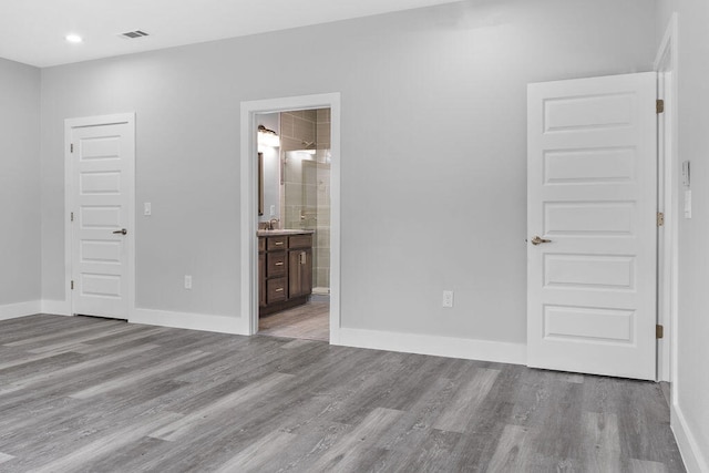 unfurnished bedroom featuring light wood-type flooring and connected bathroom