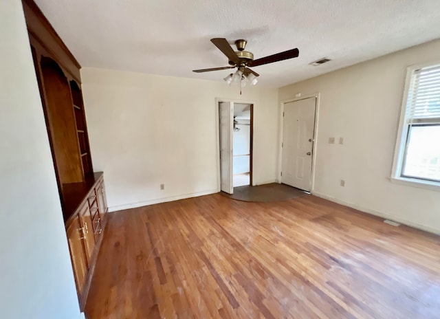 interior space with ceiling fan, a textured ceiling, and light wood-type flooring