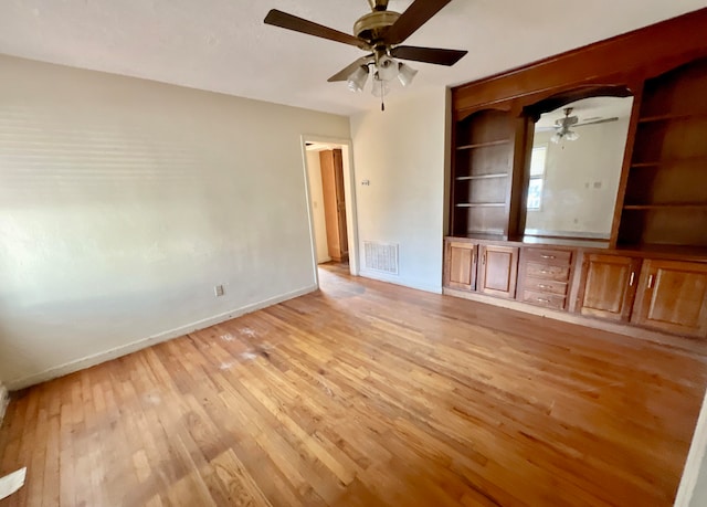 unfurnished living room featuring ceiling fan, built in features, and light hardwood / wood-style floors