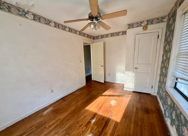 unfurnished bedroom featuring ceiling fan, dark wood-type flooring, and a textured ceiling