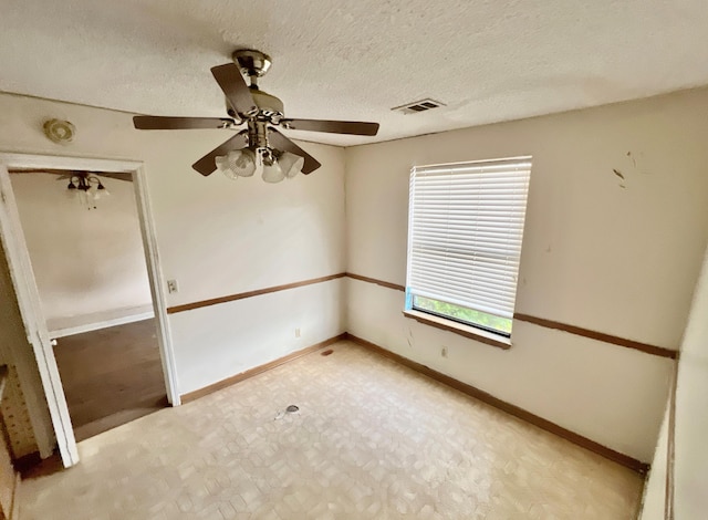 empty room with ceiling fan and a textured ceiling