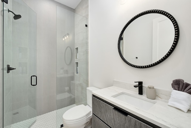 bathroom featuring toilet, vanity, and a shower with door