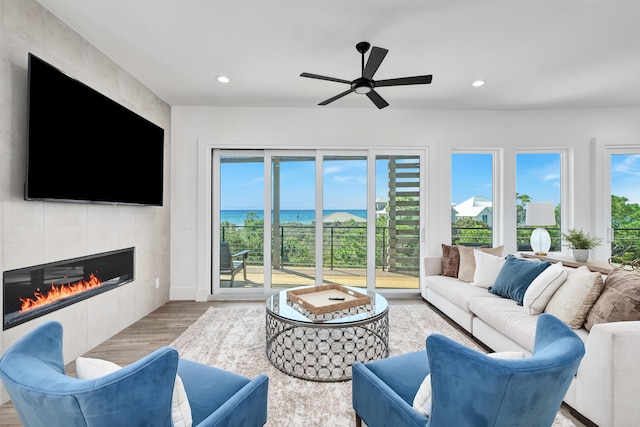 living room with a tile fireplace, light hardwood / wood-style floors, and ceiling fan