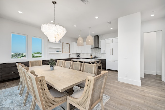 dining room with sink, a chandelier, and light hardwood / wood-style floors