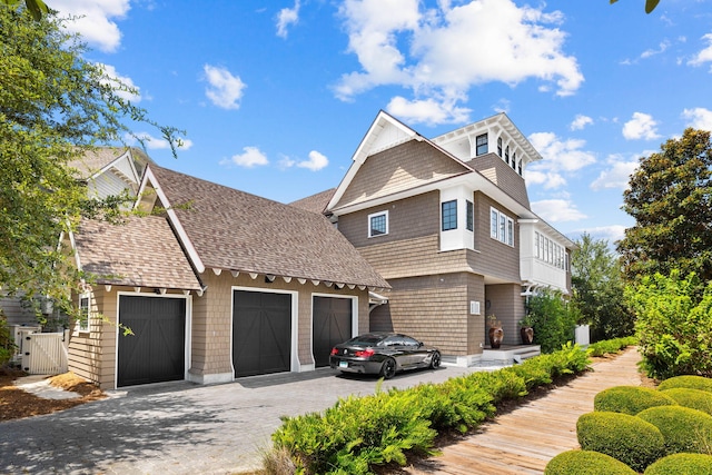 view of front of house featuring a garage, aphalt driveway, and roof with shingles