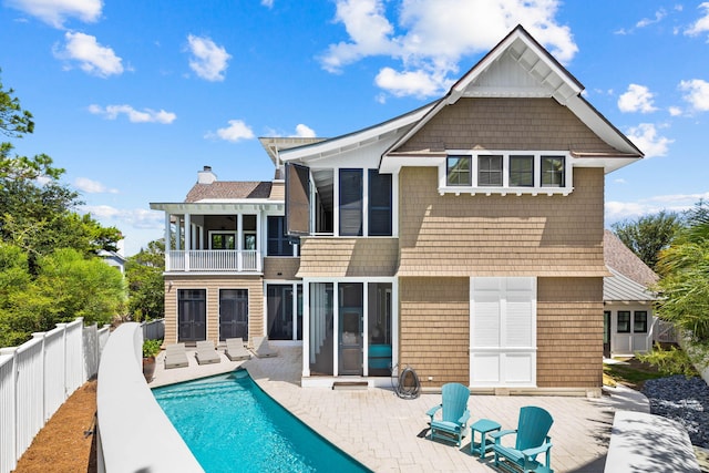 rear view of property with a fenced in pool, a sunroom, a balcony, and a patio