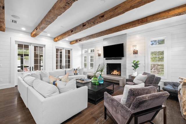 living area with dark wood-style flooring, a healthy amount of sunlight, beamed ceiling, and visible vents