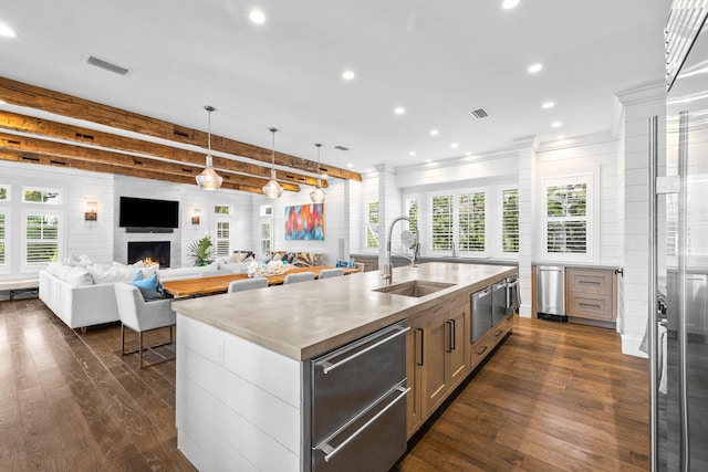 kitchen with a large fireplace, a sink, visible vents, and dark wood-style floors