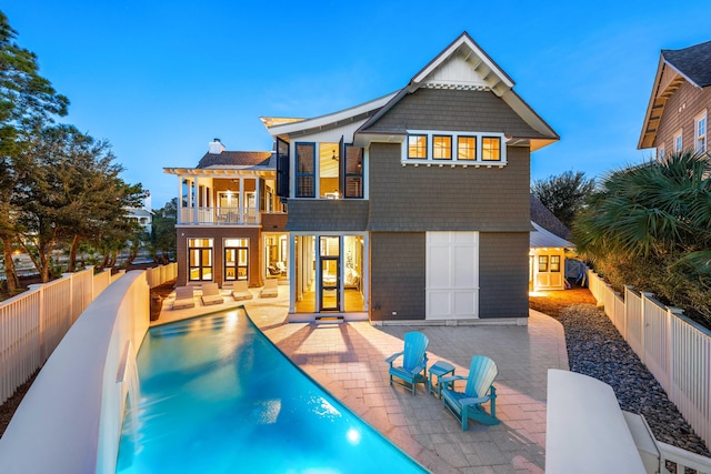 back of property featuring a balcony, a fenced in pool, and a patio