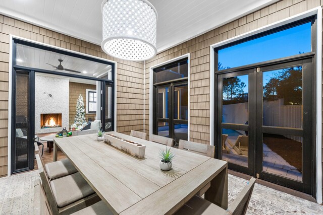 dining area featuring a notable chandelier, a fireplace, wood finished floors, and wooden walls