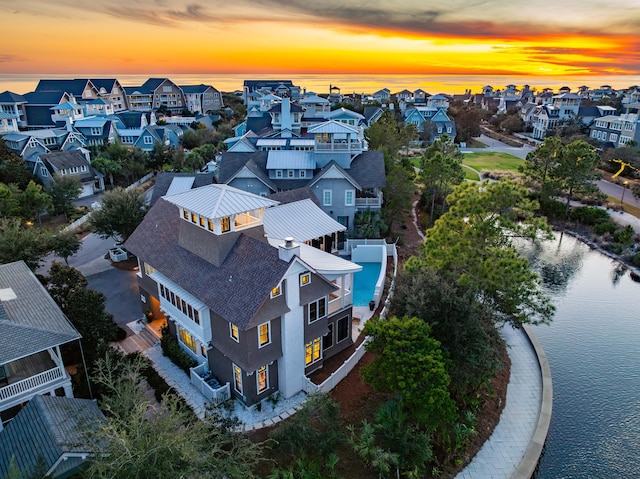 aerial view at dusk with a residential view and a water view