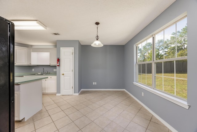 kitchen featuring white cabinets, decorative light fixtures, plenty of natural light, and black fridge