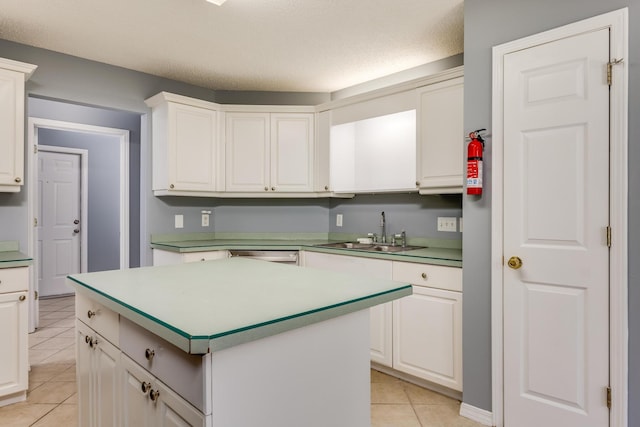 kitchen with white cabinets, light tile patterned floors, sink, a textured ceiling, and a center island