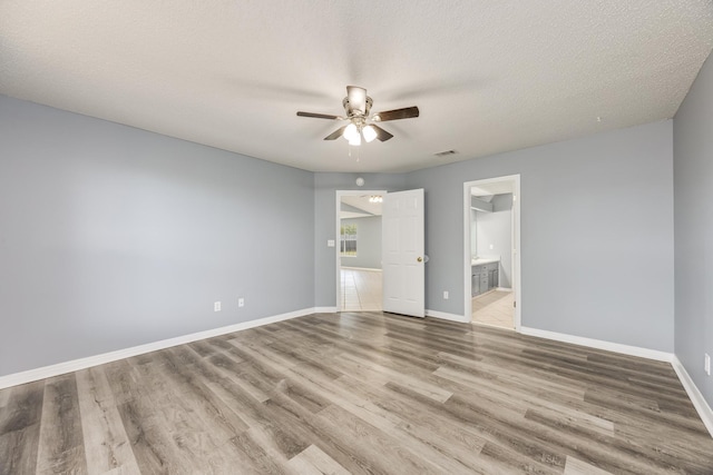 unfurnished bedroom featuring a spacious closet, ceiling fan, light hardwood / wood-style floors, and a textured ceiling