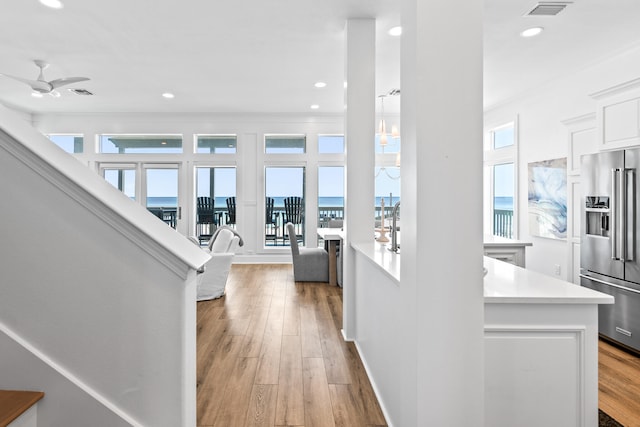 hallway featuring a water view, light hardwood / wood-style flooring, and a wealth of natural light