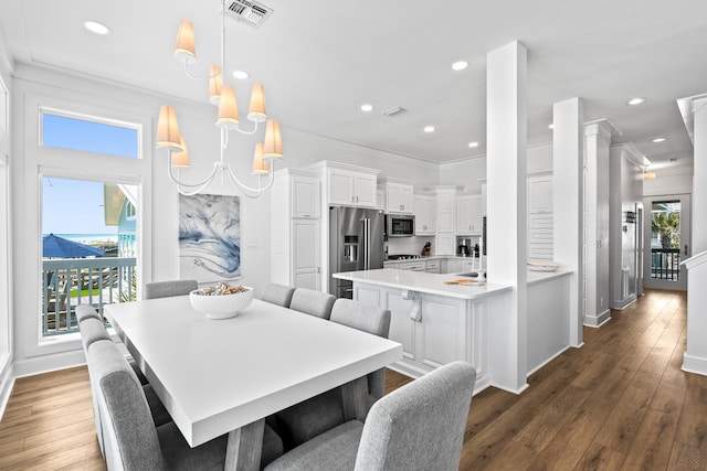 dining space featuring dark wood-type flooring, ornamental molding, and a healthy amount of sunlight