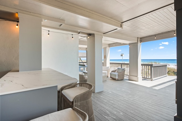 wooden deck featuring a beach view and a water view