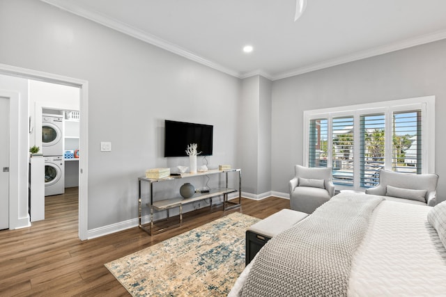 bedroom with dark wood-type flooring, crown molding, and stacked washer and dryer