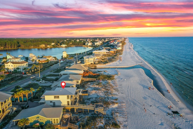 aerial view at dusk with a water view and a beach view