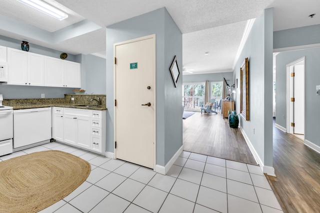 kitchen featuring white appliances, sink, light wood-type flooring, a textured ceiling, and white cabinets