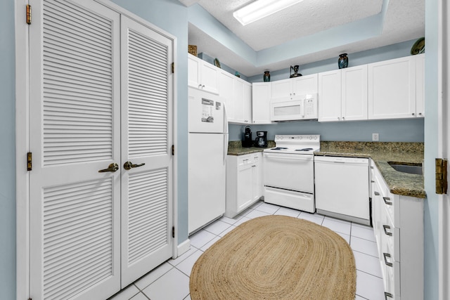 kitchen with white cabinetry, a textured ceiling, white appliances, and light tile patterned flooring