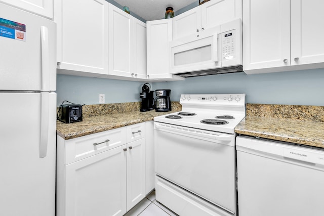 kitchen with white cabinets, light stone countertops, light tile patterned floors, and white appliances