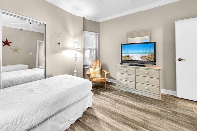 bedroom featuring hardwood / wood-style flooring, ornamental molding, electric panel, and a textured ceiling