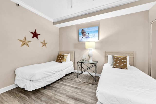 bedroom with crown molding, a textured ceiling, and hardwood / wood-style flooring