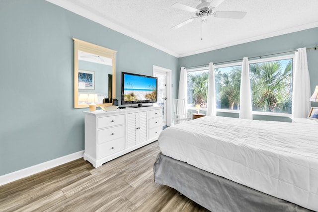 bedroom featuring ornamental molding, light hardwood / wood-style flooring, a textured ceiling, and ceiling fan