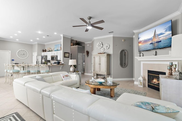 living room featuring crown molding, ceiling fan, a tile fireplace, and light tile patterned floors